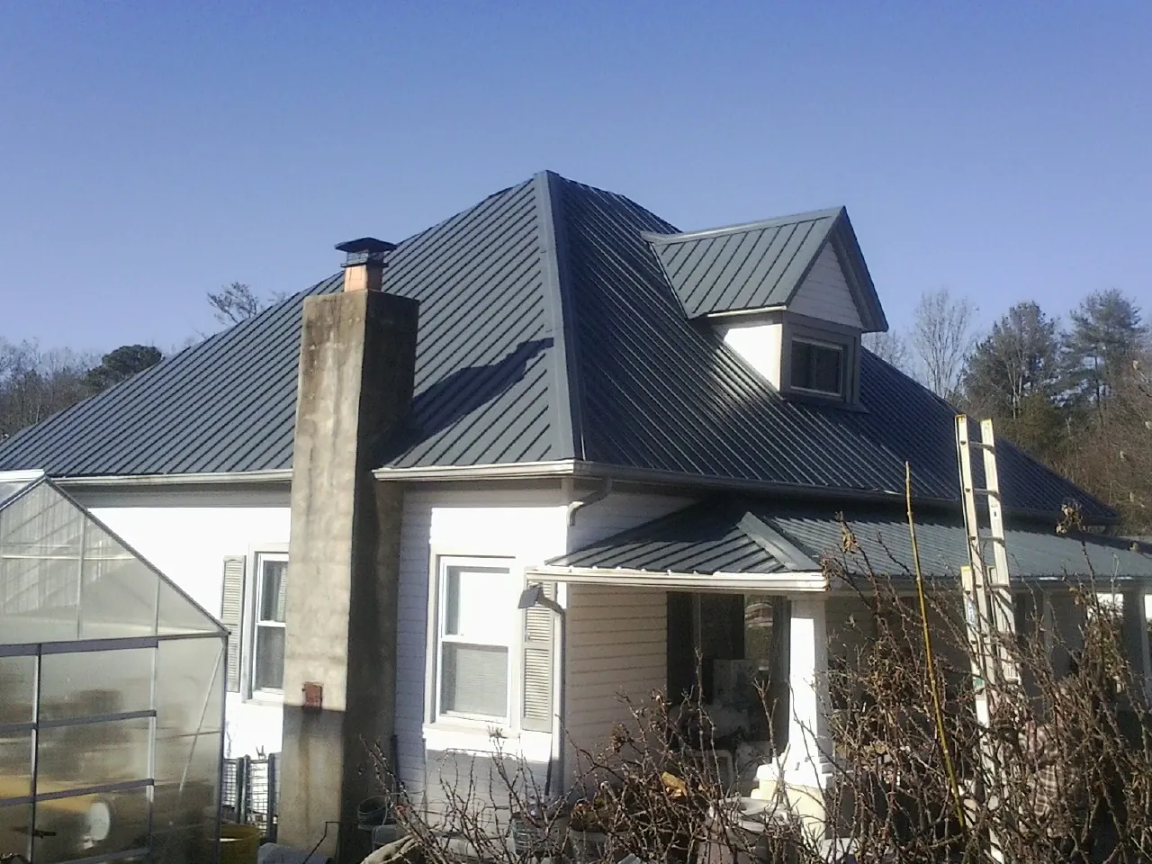 Dark blue standing seam metal roof on a white farmhouse with dormer — Slate & Tile Roof Repair by Roofing Brothers in Kimberton