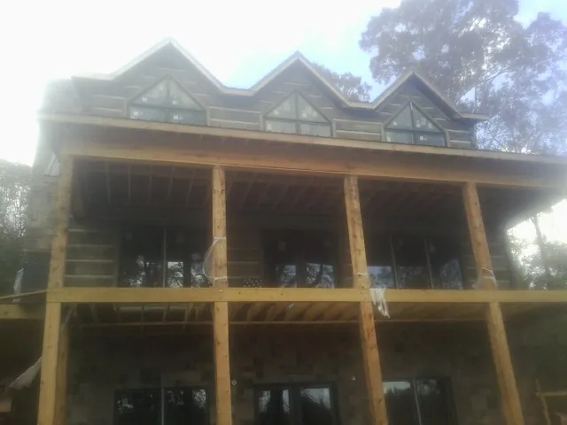 Dormers and porch framing on a large log home under construction — Roof Coating work by our crew in Kimberton