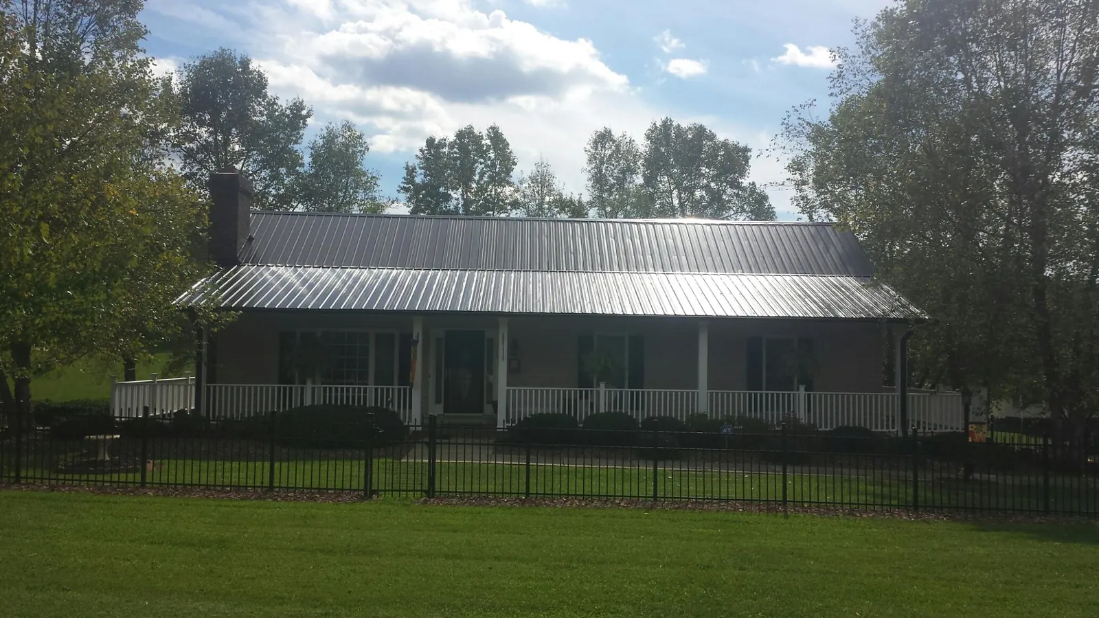 Gray metal roof on a brick ranch with a full width front porch — Gutter Guard Installation work by our crew in Kimberton