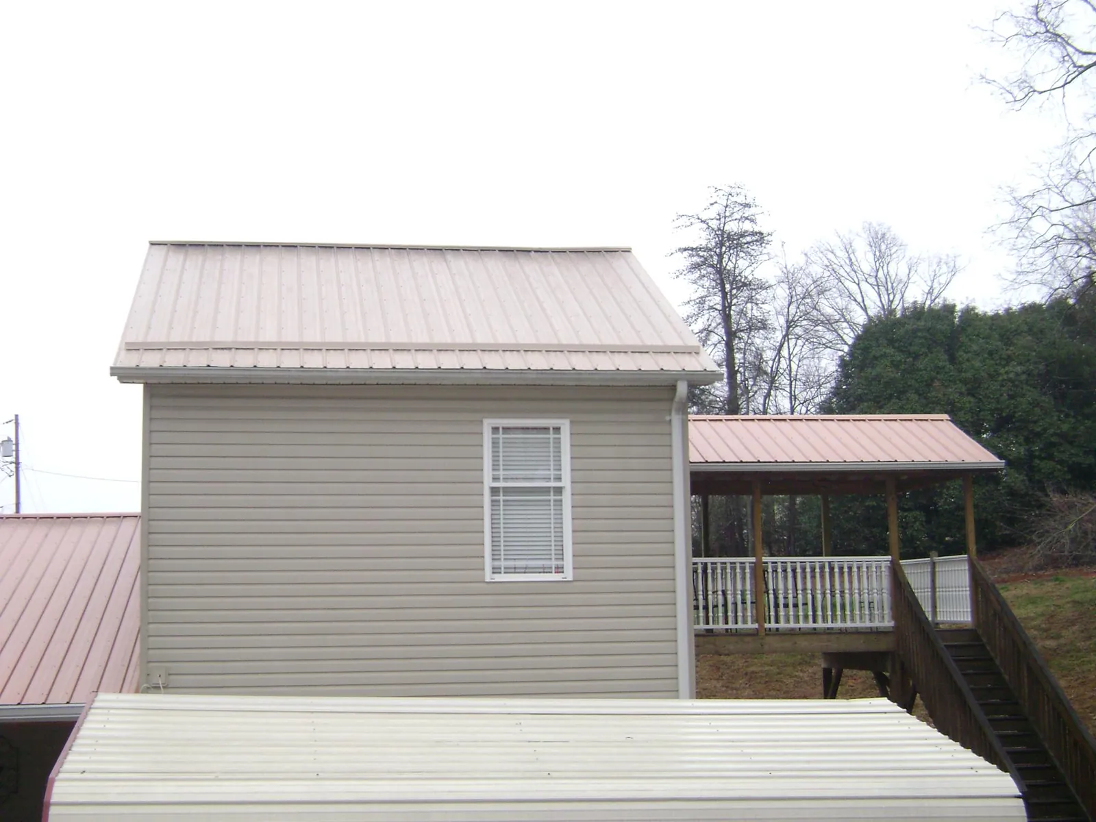Tan metal roofs on a two story addition and attached porch, from a Roof Replacement job in Kimberton