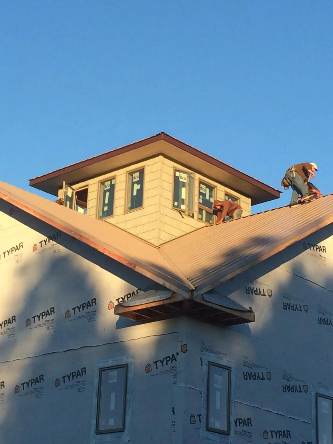Roofers working around a rooftop cupola on a new metal roof at sunset — Roof Waterproofing in Kimberton by Roofing Brothers